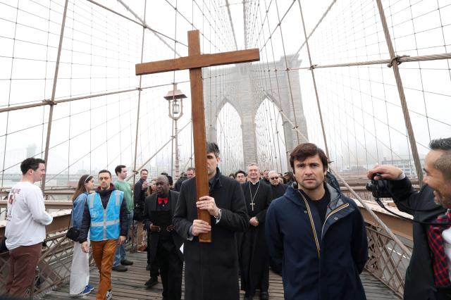 People participate in the “Way of the Cross” over the Brooklyn Bridge on Good Friday in New York on April 3, 2026. Christian believers around the world mark the Holy Week of Easter remembering the crucifixion and resurrection of Jesus Christ. (Photo by TIMOTHY A. CLARY / AFP)
