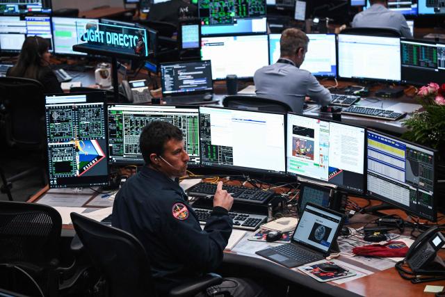 Artemis II controllers monitor the progress of the Orion spacecraft in the White Flight Control Room at Johnson Space Center in Houston, Texas, on April 3, 2026. Four Artemis astronauts were zooming towards the Moon late April 2 after a major engine firing, a milestone that commits NASA to the first crewed lunar flyby in more than half a century. With enough thrust to accelerate a stationary car to highway driving speed in less than three seconds, the Orion capsule engine blasted the astronauts on their trajectory towards the Moon, which they now will loop as part of the 10-day Artemis II mission. (Photo by RONALDO SCHEMIDT / AFP)