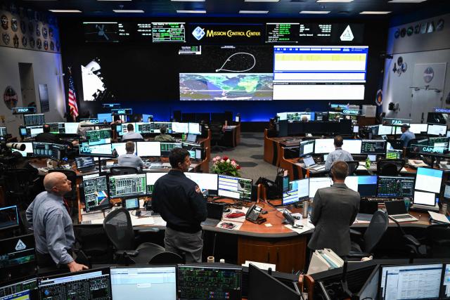 Artemis II controllers monitor the progress of the Orion spacecraft in the White Flight Control Room at Johnson Space Center in Houston, Texas, on April 3, 2026. Four Artemis astronauts were zooming towards the Moon late April 2 after a major engine firing, a milestone that commits NASA to the first crewed lunar flyby in more than half a century. With enough thrust to accelerate a stationary car to highway driving speed in less than three seconds, the Orion capsule engine blasted the astronauts on their trajectory towards the Moon, which they now will loop as part of the 10-day Artemis II mission. (Photo by RONALDO SCHEMIDT / AFP)