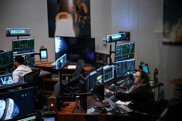 Artemis II controllers monitor the progress of the Orion spacecraft in the White Flight Control Room at Johnson Space Center in Houston, Texas, on April 3, 2026. Four Artemis astronauts were zooming towards the Moon late April 2 after a major engine firing, a milestone that commits NASA to the first crewed lunar flyby in more than half a century. With enough thrust to accelerate a stationary car to highway driving speed in less than three seconds, the Orion capsule engine blasted the astronauts on their trajectory towards the Moon, which they now will loop as part of the 10-day Artemis II mission. (Photo by RONALDO SCHEMIDT / AFP)