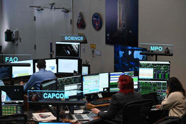 Artemis II controllers monitor the progress of the Orion spacecraft in the White Flight Control Room at Johnson Space Center in Houston, Texas, on April 3, 2026. Four Artemis astronauts were zooming towards the Moon late April 2 after a major engine firing, a milestone that commits NASA to the first crewed lunar flyby in more than half a century. With enough thrust to accelerate a stationary car to highway driving speed in less than three seconds, the Orion capsule engine blasted the astronauts on their trajectory towards the Moon, which they now will loop as part of the 10-day Artemis II mission. (Photo by RONALDO SCHEMIDT / AFP)