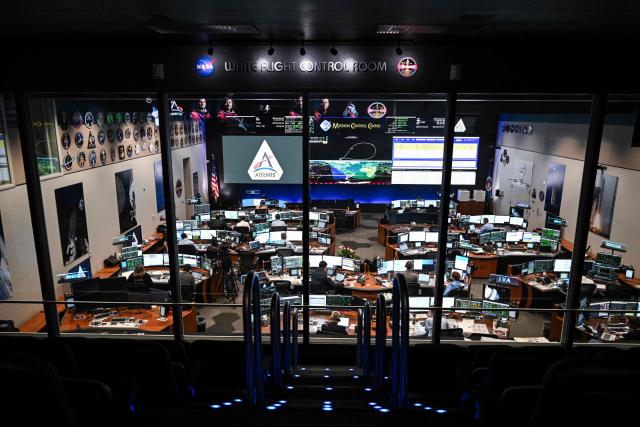 Artemis II controllers monitor the progress of the Orion spacecraft in the White Flight Control Room at Johnson Space Center in Houston, Texas, on April 3, 2026. Four Artemis astronauts were zooming towards the Moon late April 2 after a major engine firing, a milestone that commits NASA to the first crewed lunar flyby in more than half a century. With enough thrust to accelerate a stationary car to highway driving speed in less than three seconds, the Orion capsule engine blasted the astronauts on their trajectory towards the Moon, which they now will loop as part of the 10-day Artemis II mission. (Photo by RONALDO SCHEMIDT / AFP)