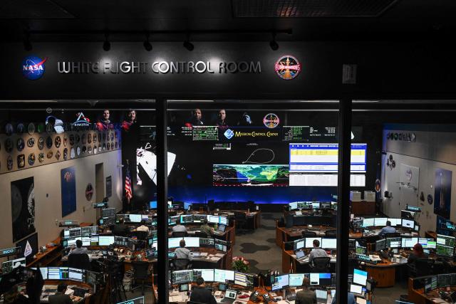 Artemis II controllers monitor the progress of the Orion spacecraft in the White Flight Control Room at Johnson Space Center in Houston, Texas, on April 3, 2026. Four Artemis astronauts were zooming towards the Moon late April 2 after a major engine firing, a milestone that commits NASA to the first crewed lunar flyby in more than half a century. With enough thrust to accelerate a stationary car to highway driving speed in less than three seconds, the Orion capsule engine blasted the astronauts on their trajectory towards the Moon, which they now will loop as part of the 10-day Artemis II mission. (Photo by RONALDO SCHEMIDT / AFP)