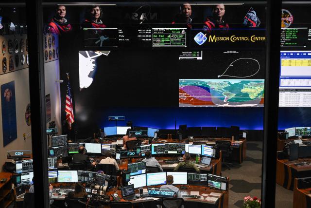 Artemis II controllers monitor the progress of the Orion spacecraft in the White Flight Control Room at Johnson Space Center in Houston, Texas, on April 3, 2026. Four Artemis astronauts were zooming towards the Moon late April 2 after a major engine firing, a milestone that commits NASA to the first crewed lunar flyby in more than half a century. With enough thrust to accelerate a stationary car to highway driving speed in less than three seconds, the Orion capsule engine blasted the astronauts on their trajectory towards the Moon, which they now will loop as part of the 10-day Artemis II mission. (Photo by RONALDO SCHEMIDT / AFP)