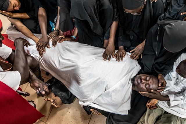 A group of parishioners weep as they hand over a man portraying Jesus Christ wrapped in white cloth, during a re-enactment commemorating the crucifixion of Jesus Christ, in Bakoteh, The Gambia, on April 3, 2026. (Photo by MUHAMADOU BITTAYE / AFP)