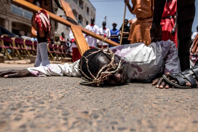 A man portraying Jesus Christ falls to the ground during a Good Friday re-enactment in Bakoteh, The Gambia, on April 3, 2026. (Photo by MUHAMADOU BITTAYE / AFP)