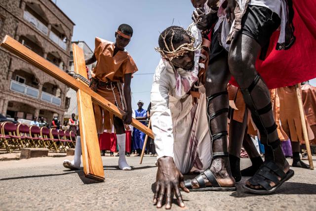 A man portraying Jesus Christ falls to the ground during a Good Friday re-enactment in Bakoteh, The Gambia, on April 3, 2026. (Photo by MUHAMADOU BITTAYE / AFP)