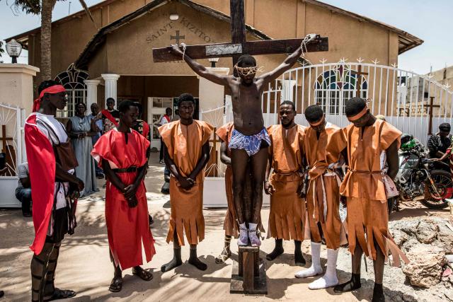 A man is tied to wooden cross during a re-enactment commemorating the crucifixion of Jesus Christ, in Bakoteh, The Gambia, on April 3, 2026. (Photo by MUHAMADOU BITTAYE / AFP)