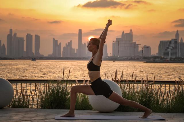 A woman practices yoga in front of the Dubai skyline in Creek Harbour on April 3, 2026. (Photo by FADEL SENNA / AFP)