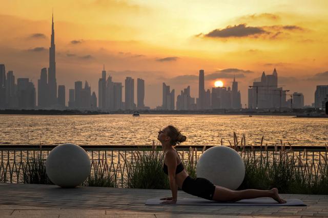 A woman practices yoga in front of the Dubai skyline, with the Burj Khalifa, the world’s tallest building, seen from Creek Harbour on April 3, 2026. (Photo by FADEL SENNA / AFP)