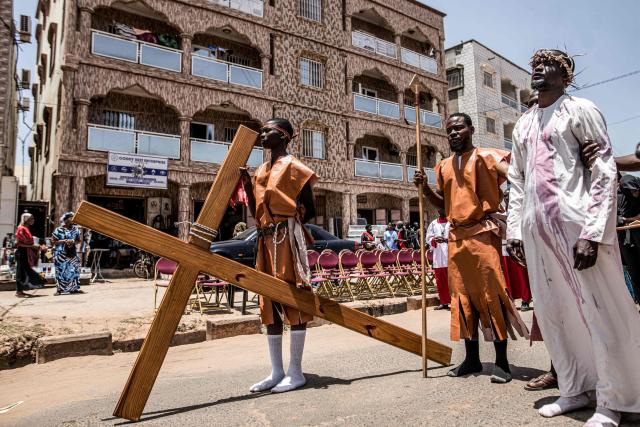 A man portraying Jesus Christ stands next to a cross during a Good Friday re-enactment in Bakoteh, The Gambia, on April 3, 2026. (Photo by MUHAMADOU BITTAYE / AFP)