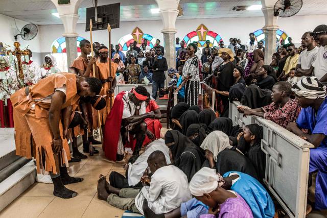 A group of parishioners weep as they hand over the body of a man portraying Jesus Christ during a Good Friday re-enactment at a church in Bakoteh, The Gambia, on April 3, 2026. (Photo by MUHAMADOU BITTAYE / AFP)