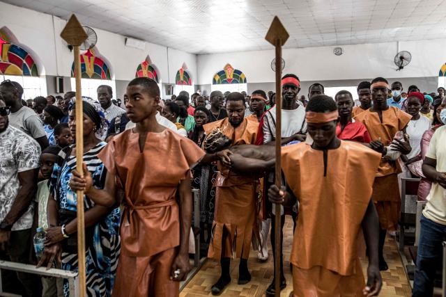 Christian faithful watch as a man portraying Jesus Christ is carried during a re-enactment commemorating the crucifixion of Jesus Christ, in Bakoteh, The Gambia, on April 3, 2026. (Photo by MUHAMADOU BITTAYE / AFP)