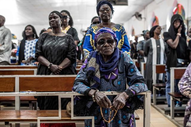 A woman kneels in reverence during a Good Friday service at a church in Bakoteh, The Gambia, on April 3, 2026. (Photo by MUHAMADOU BITTAYE / AFP)