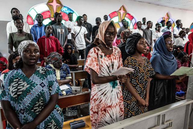 Worshippers sing hymns during a Good Friday service at a church in Bakoteh, The Gambia, on April 3, 2026. (Photo by MUHAMADOU BITTAYE / AFP)