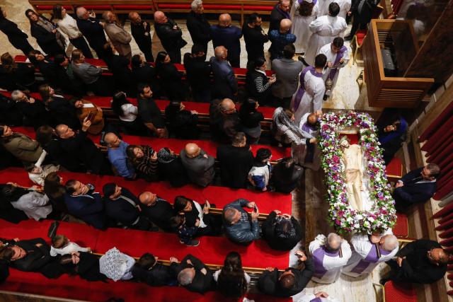 Alter boys and clergymen carry a statue representing the body of Jesus Christ after he was taken down the cross during the Good Friday mass at the Our Lady of Perpetual Help Chaldean Catholic Church in Arbil, the capital of the autonomous Kurdish region of northern Iraq, on April 3, 2026. (Photo by Safin HAMID / AFP)