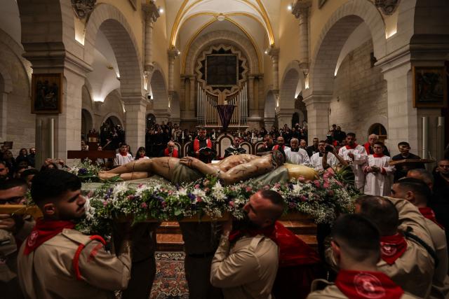 Palestinian scouts carry a statue representing the body of Jesus Christ after he was taken down the cross, during the Good Friday mass at the Catholic Church of Saint Catherine in the Israeli-occupied West Bank city of Bethlehem on April 3, 2026. (Photo by HAZEM BADER / AFP)
