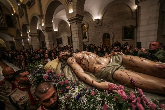 Palestinian scouts carry a statue representing the body of Jesus Christ after he was taken down the cross, during the Good Friday mass at the Catholic Church of Saint Catherine in the Israeli-occupied West Bank city of Bethlehem on April 3, 2026. (Photo by HAZEM BADER / AFP)