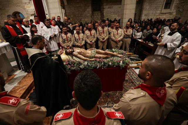 Palestinian scouts and members of the clergy stand around a statue representing the body of Jesus Christ after he was taken down the cross, during the Good Friday mass at the Catholic Church of Saint Catherine in the Israeli-occupied West Bank city of Bethlehem on April 3, 2026. (Photo by HAZEM BADER / AFP)
