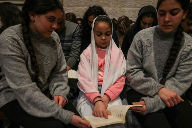 A young Palestinian Christian worshipper attends a Good Friday mass at the Catholic Church of Saint Catherine in the Israeli-occupied West Bank city of Bethlehem on April 3, 2026. (Photo by HAZEM BADER / AFP)