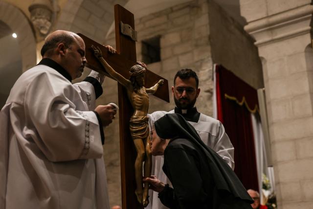 A nuns kisses a crucifix during the Good Friday mass at the Catholic Church of Saint Catherine in the Israeli-occupied West Bank city of Bethlehem on April 3, 2026. (Photo by HAZEM BADER / AFP)