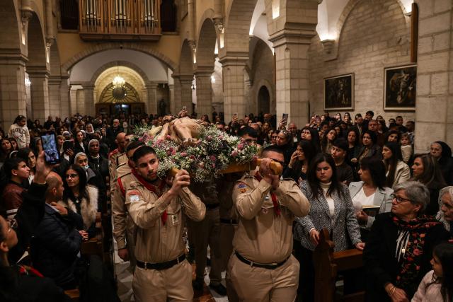 Palestinian scouts carry a statue representing the body of Jesus Christ after he was taken down the cross, during the Good Friday mass at the Catholic Church of Saint Catherine in the Israeli-occupied West Bank city of Bethlehem on April 3, 2026. (Photo by HAZEM BADER / AFP)