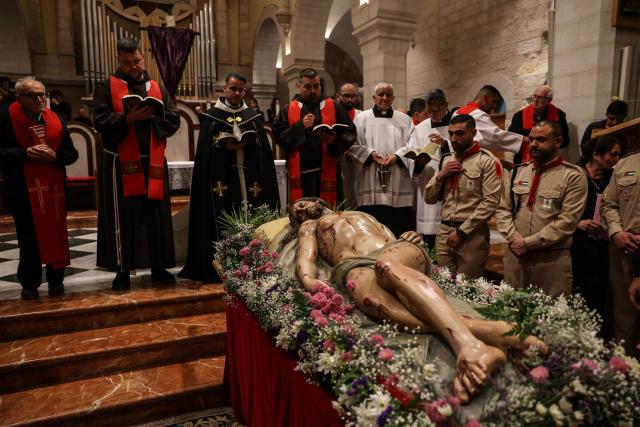 Palestinian scouts and members of the clergy stand around a statue representing the body of Jesus Christ after he was taken down the cross, during the Good Friday mass at the Catholic Church of Saint Catherine in the Israeli-occupied West Bank city of Bethlehem on April 3, 2026. (Photo by HAZEM BADER / AFP)