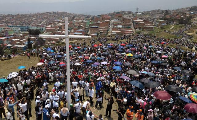 Catholic faithfuls lift a cross during the Via Crucis procession as part of Good Friday celebrations at the Tree of Life in Ciudad Bolivar, south Bogota on April 3, 2026. (Photo by Raul ARBOLEDA / AFP)
