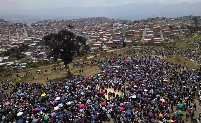 Catholic faithfuls lift a cross during the Via Crucis procession as part of Good Friday celebrations at the Tree of Life in Ciudad Bolivar, south Bogota on April 3, 2026. (Photo by Raul ARBOLEDA / AFP)