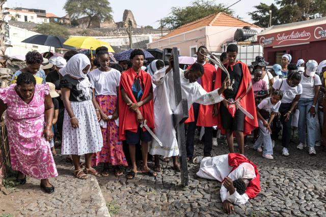 A young man portraying Jesus Christ lies on the ground as another one pretends to whip him during a Good Friday Way of the Cross procession in Cidade Velha, Cape Verde, on April 3, 2026. The city was founded in 1462 by Portuguese traders and was the first colonial outpost in the tropics. Formerly known as Ribeira Grande, the town has a rich historical heritage including Our Lady of the Rosary, a church built in 1495 by Portuguese settlers. The town became a UNESCO World Heritage Site in 2009. (Photo by PATRICK MEINHARDT / AFP)