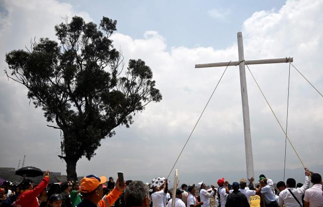 Catholic faithfuls lift a cross during the Via Crucis procession as part of Good Friday celebrations at the Tree of Life in Ciudad Bolivar, south Bogota on April 3, 2026. (Photo by Raul ARBOLEDA / AFP)