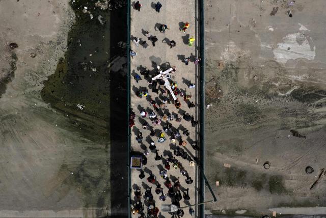 This aerial view shows Catholic faithful, migrants, and advocates participating in the Migrant Walk of the Cross as part of the Holy Week celebrations in Tijuana, Baja California state, Mexico on April 3, 2026. (Photo by Guillermo Arias / AFP)