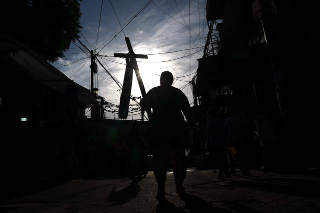 A Catholic faithful holds a cross during a procession marking the Way of the Cross on Good Friday at the Padre Carlos Mujica shantytown (known as Villa 31) in Buenos Aires on April 3, 2026. (Photo by Luis ROBAYO / AFP)