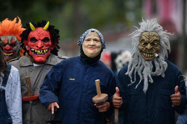 Masked residents walk along a street as part of a tradition after the Good Friday procession in Petoa, Santa Barbara department, Honduras, on April 3, 2026. (Photo by Orlando SIERRA / AFP)