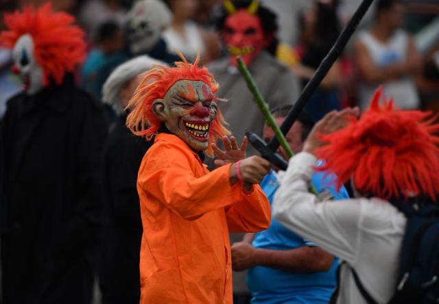 Masked residents fight with swords as part of a tradition after the Good Friday procession in Petoa, Santa Barbara department, Honduras, on April 3, 2026. (Photo by Orlando SIERRA / AFP)