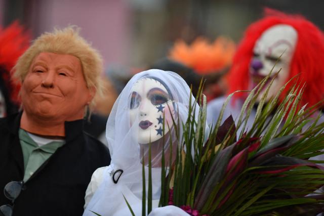 A resident with a mask depicting US President Donald Trump pretends to marry a woman witrh a mask depicting a bride as part of a tradition after the Good Friday procession in Petoa, Santa Barbara department, Honduras, on April 3, 2026. (Photo by Orlando SIERRA / AFP)