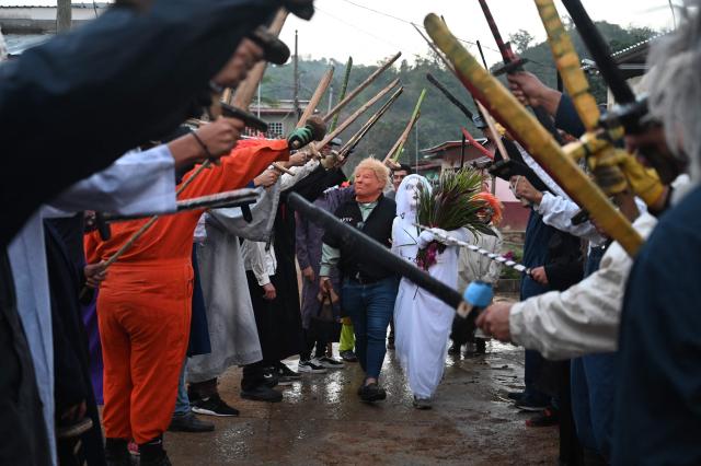 A resident with a mask depicting US President Donald Trump pretends to marry a woman with a bride's costume as part of a tradition after the Good Friday procession in Petoa, Santa Barbara department, Honduras, on April 3, 2026. (Photo by Orlando SIERRA / AFP)
