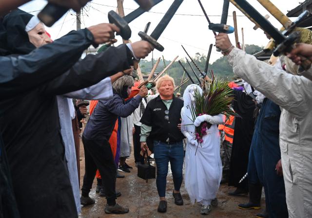 A resident with a mask depicting US President Donald Trump pretends to marry a woman with a bride's costume as part of a tradition after the Good Friday procession in Petoa, Santa Barbara department, Honduras, on April 3, 2026. (Photo by Orlando SIERRA / AFP)