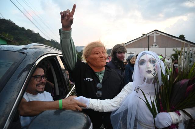 A resident with a mask depicting US President Donald Trump pretends to marry a woman with a bride's costume as part of a tradition after the Good Friday procession in Petoa, Santa Barbara department, Honduras, on April 3, 2026. (Photo by Orlando SIERRA / AFP)