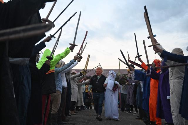 A resident with a mask depicting US President Donald Trump pretends to marry a woman with a bride's costume as part of a tradition after the Good Friday procession in Petoa, Santa Barbara department, Honduras, on April 3, 2026. (Photo by Orlando SIERRA / AFP)