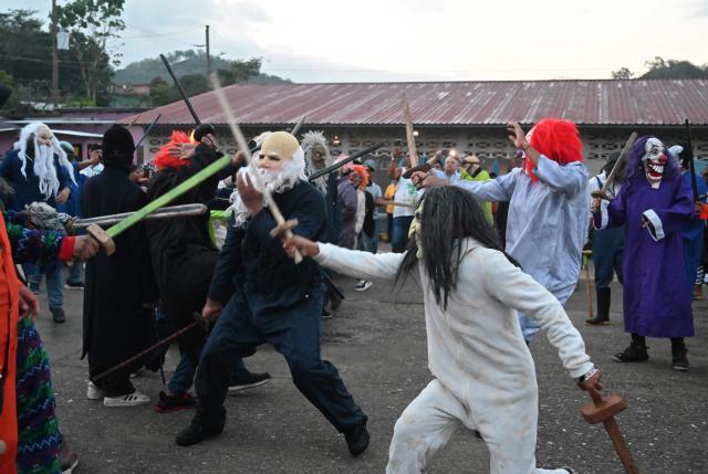 Masked residents fight with swords as part of a tradition after the Good Friday procession in Petoa, Santa Barbara department, Honduras, on April 3, 2026. (Photo by Orlando SIERRA / AFP)