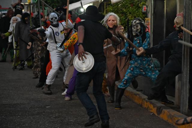 Masked residents fight with swords as part of a tradition after the Good Friday procession in Petoa, Santa Barbara department, Honduras, on April 3, 2026. (Photo by Orlando SIERRA / AFP)
