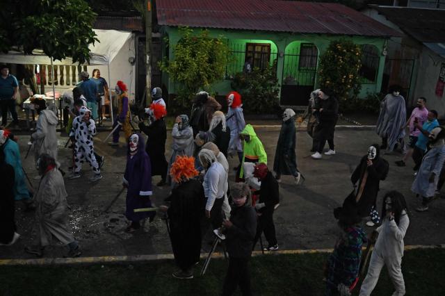 Masked residents walk along a street as part of a tradition during the Good Friday procession in Petoa, Santa Barbara department, Honduras, on April 3, 2026. (Photo by Orlando SIERRA / AFP)