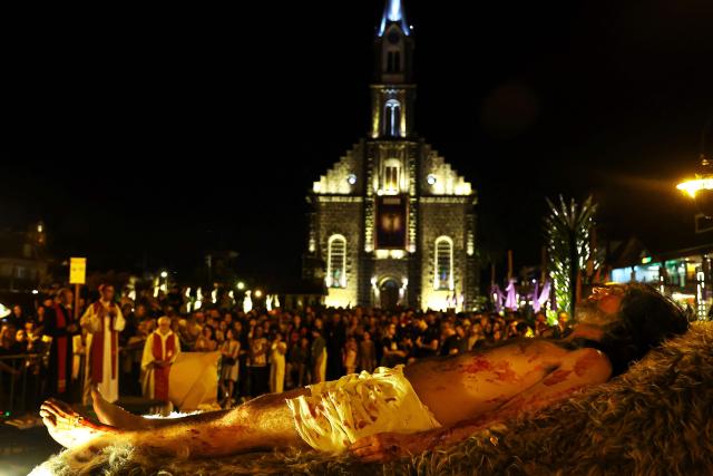 Catholic faithful take part in the traditional Stations of the Cross procession, reenacting the final hours of Jesus Christ’s life, lighting up the streets with torches and candles in Gramado, Rio Grande do Sul state, Brazil on April 3, 2026. (Photo by SILVIO AVILA / AFP)