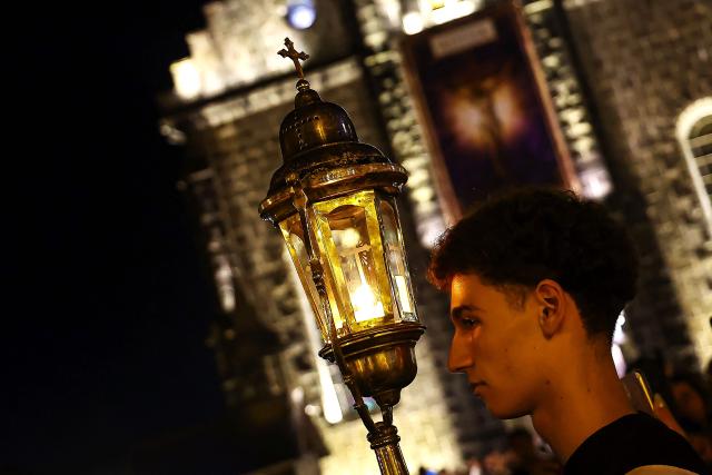 A Catholic faithful holds a torch as he takes part in the traditional Stations of the Cross procession, reenacting the final hours of Jesus Christ’s life, lighting up the streets with torches and candles in Gramado, Rio Grande do Sul state, Brazil on April 3, 2026. (Photo by SILVIO AVILA / AFP)