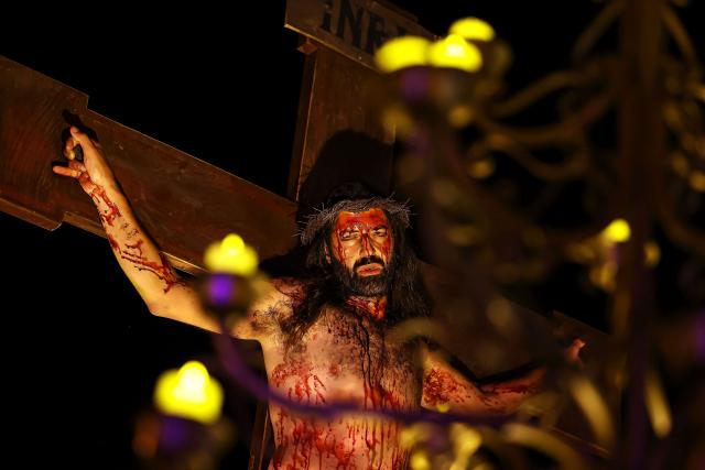 A Catholic faithful enacts the Passion of Jesus Christ as he takes part in the traditional Stations of the Cross procession, reenacting the final hours of Jesus Christ’s life, lighting up the streets with torches and candles in Gramado, Rio Grande do Sul state, Brazil on April 3, 2026. (Photo by SILVIO AVILA / AFP)