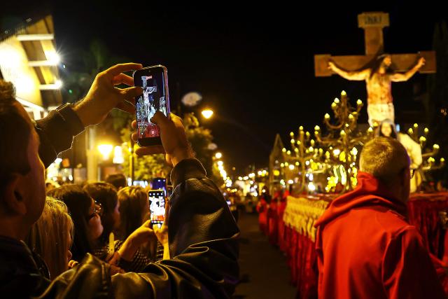 A Catholic faithful takes a picture to the traditional Stations of the Cross procession, reenacting the final hours of Jesus Christ’s life, lighting up the streets with torches and candles in Gramado, Rio Grande do Sul state, Brazil on April 3, 2026. (Photo by SILVIO AVILA / AFP)