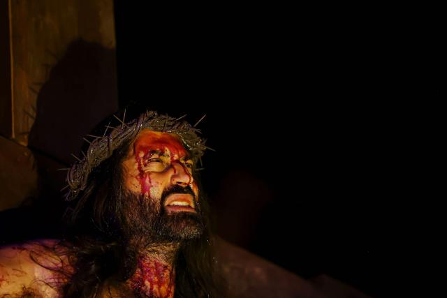 A Catholic faithful enacts the Passion of Jesus Christ as he takes part in the traditional Stations of the Cross procession, reenacting the final hours of Jesus Christ’s life, lighting up the streets with torches and candles in Gramado, Rio Grande do Sul state, Brazil on April 3, 2026. (Photo by SILVIO AVILA / AFP)
