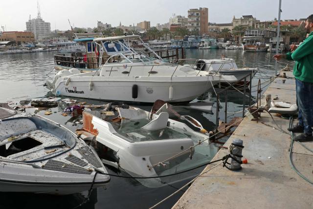 A man inspects damaged boats at the site of an Israeli strike in the port of the Lebanese coastal city of Tyre on April 4, 2026. The Israeli military said on April 3, it had struck more than 3,500 targets across Lebanon in the month since fighting with Iran-backed Hezbollah militants. Lebanon was drawn into the Middle East war on March 2 when Hezbollah launched attacks on Israel to avenge the killing of the Iranian leader. Israel has responded with broad strikes across Lebanon and a ground offensive. (Photo by Kawnat HAJU / AFP)