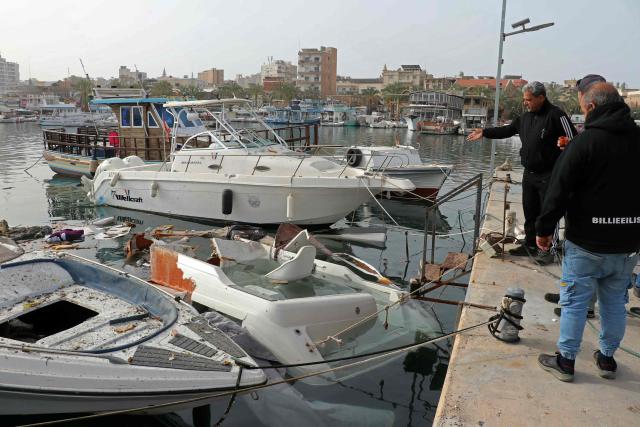 Men inspect damaged boats at the site of an Israeli strike in the port of the Lebanese coastal city of Tyre on April 4, 2026. The Israeli military said on April 3, it had struck more than 3,500 targets across Lebanon in the month since fighting with Iran-backed Hezbollah militants. Lebanon was drawn into the Middle East war on March 2 when Hezbollah launched attacks on Israel to avenge the killing of the Iranian leader. Israel has responded with broad strikes across Lebanon and a ground offensive. (Photo by Kawnat HAJU / AFP)